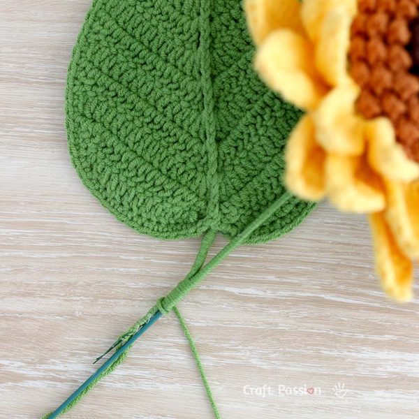 crochet sunflower leaf Realistic crochet sunflower with layered yellow petals, textured center, stem, and leaf