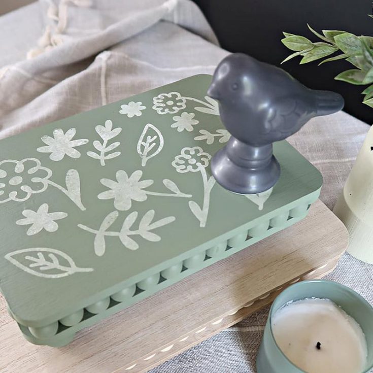 Check out this stylish wood bead riser that you can craft using two wooden cutting boards and some wooden beads from the dollar store. This wood bead riser can be a versatile decor piece that elevates your living room, whether it&rsquo;s for displaying candles, plants, or other decorative items.